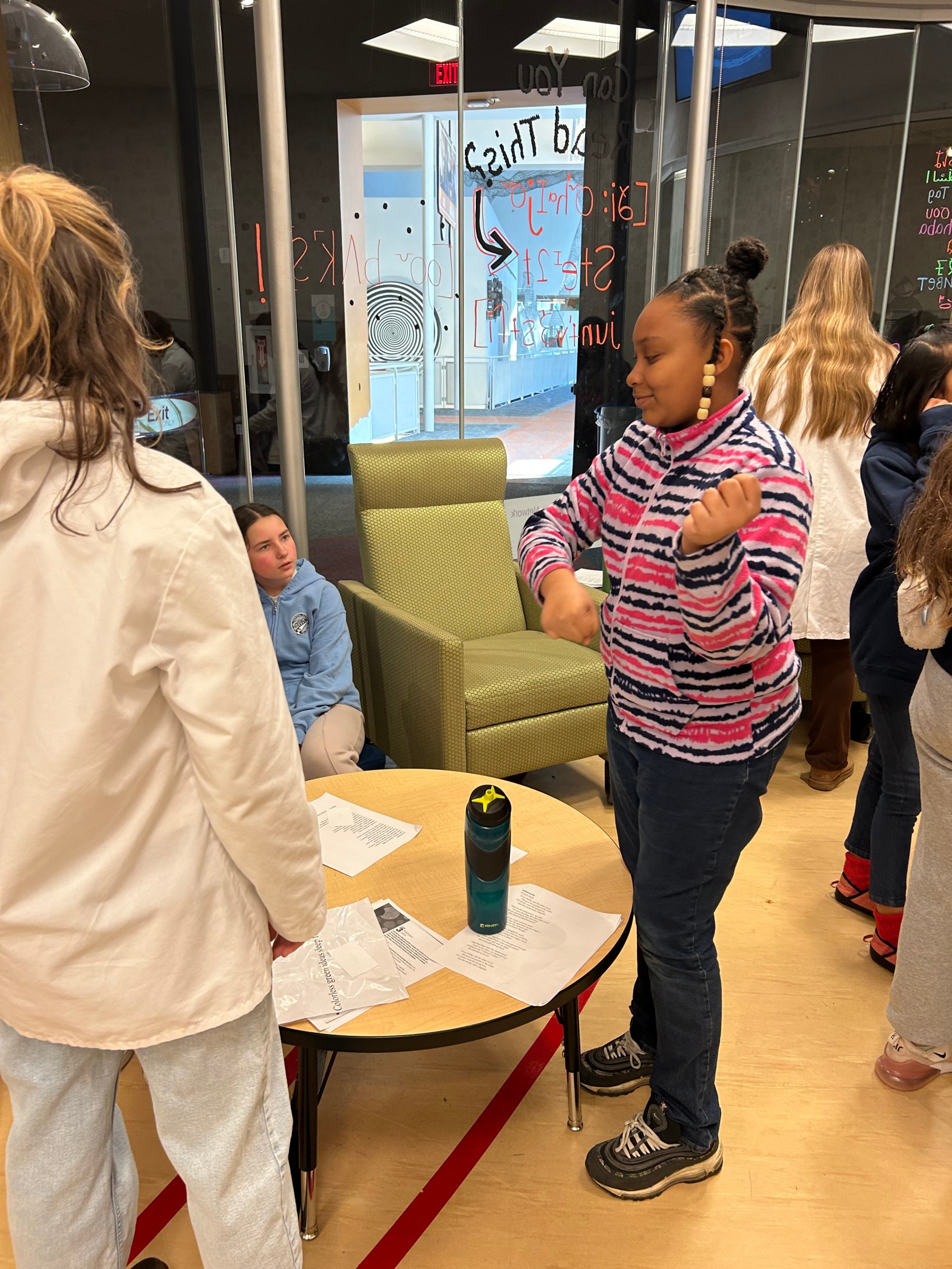 Three Girl Scouts talking with each other in an environment with low tables and armchairs