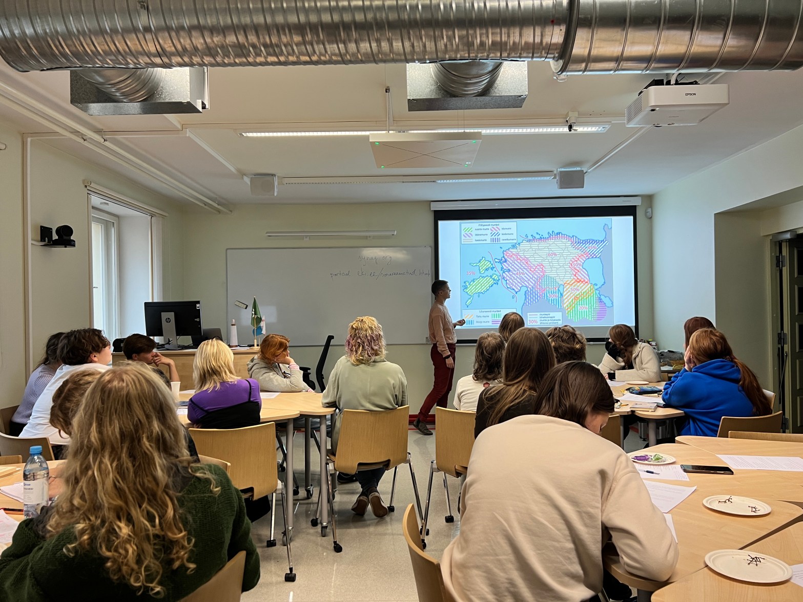 Classroom showing a language map on a projector and the backs of high school students' heads